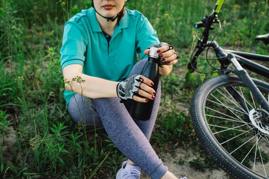 Woman in Helmet Takes a Drink During a Bike Ride photo