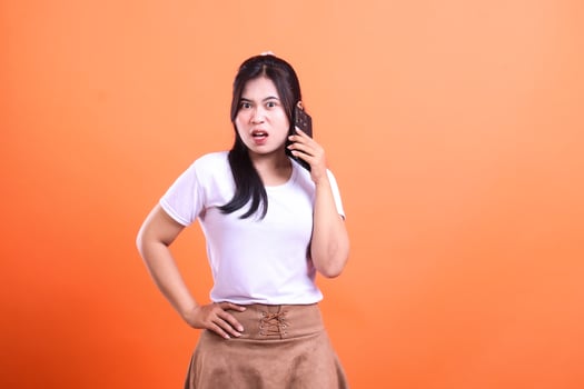 Woman on phone in front of bright background showing anger and frustration on her face photo