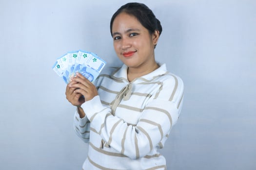 A Beautiful asian woman in sweater hold indonesian banknote isolated on white background. photo