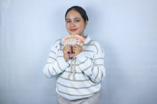 A Beautiful asian woman in sweater hold indonesian banknote isolated on white background.. photo