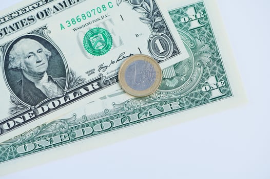 Closeup view of a euro coin resting on a one dollar bill displaying currency from different regions photo