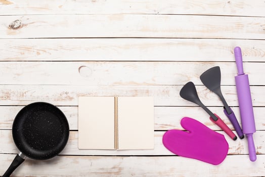 Cast iron pan and other kitchen utensils on wooden table, top view photo