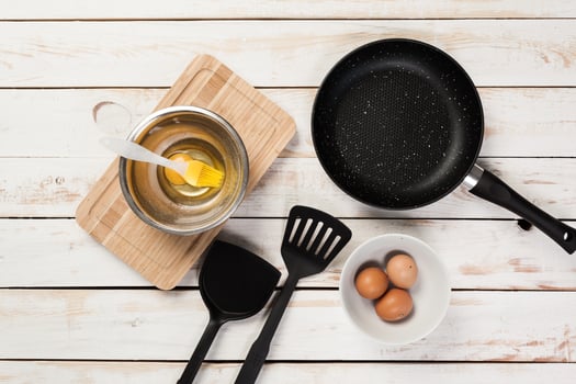 Cast iron pan and other kitchen utensils on wooden table, top view photo