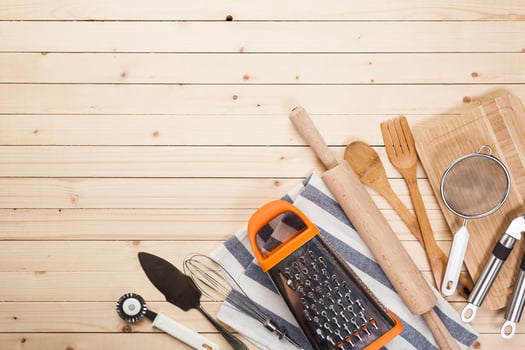 Wooden spoons and other cooking tools with blue napkins on the kitchen table. photo