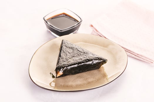 A piece of sushi on a plate with a glass of soy sauce photo