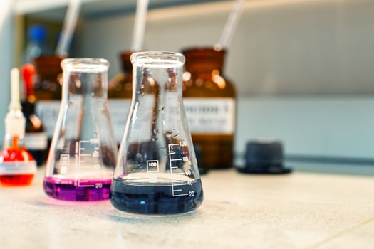 Glass containers with colored liquids on laboratory countertop during scientific experiment in modern facility photo