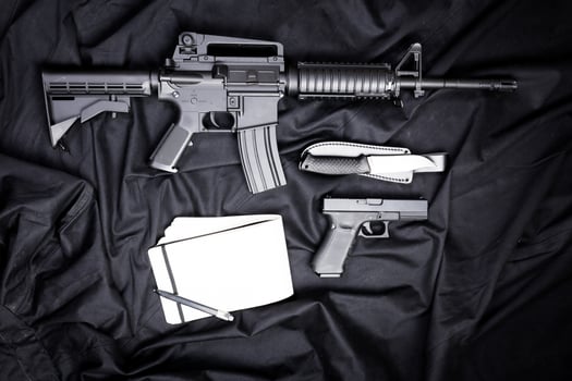 Rifle, gun, knife with sheath, compass and notebook with pen on on black cloth photo
