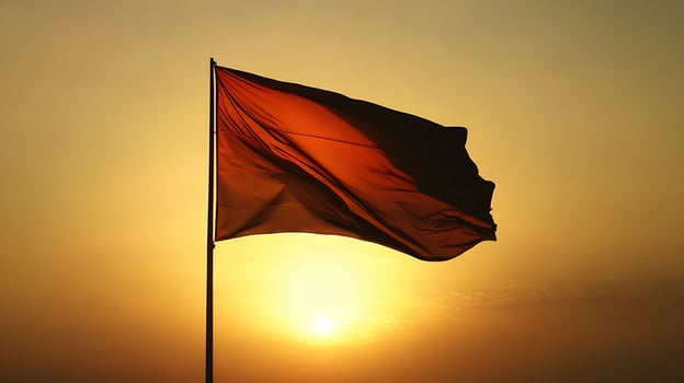 Solitary Red Flag Enveloped in Silhouette Against Golden Sunset Horizon photo