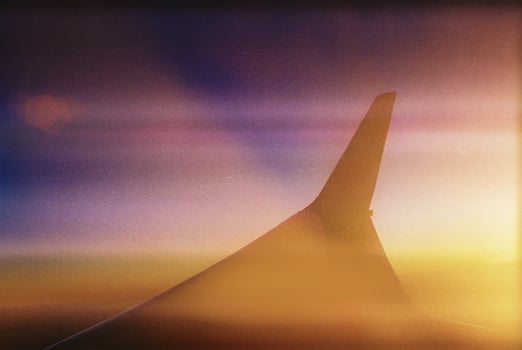 View of an airplane in flight during sunset, with the wing in the foreground photo