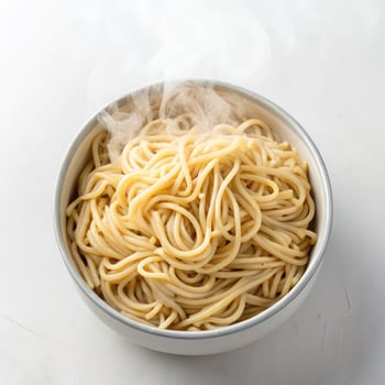 Top View of Steaming Cooked Spaghetti Noodles in a Bowl on a White Background photo