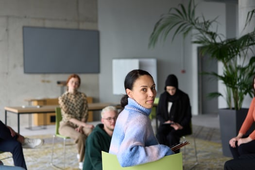 A diverse group of business professionals sits attentively in a modern office, actively participating in a training session led by an instructor, focusing on the latest technological advancements in photo