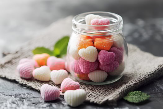 Colorful heart-shaped candies in a glass jar on black wooden background photo