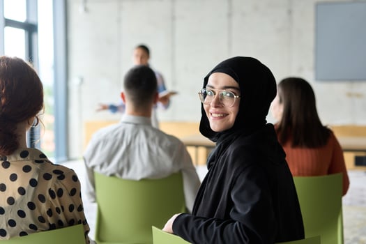 A diverse group of business professionals sits attentively in a modern office, actively participating in a training session led by an instructor, focusing on the latest technological advancements in photo