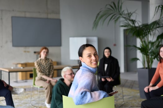 A diverse group of business professionals sits attentively in a modern office, actively participating in a training session led by an instructor, focusing on the latest technological advancements in photo