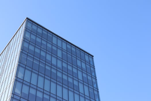 A Modern Glass Building Stands Tall Against a Clear Blue Sky Adding to Urban Aesthetics photo