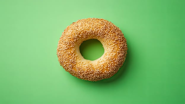 A Golden Sesame Bagel on a Green Background photo