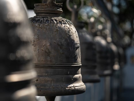 Traditional antique bells hang in an outdoor temple in Thailand. Close-up of beautiful bells lined up in a Buddhist temple or place in Thailand. Calm and believe. photo