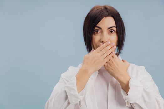 Mature woman covering her mouth with hands on blue background photo
