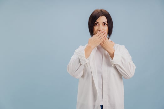 Shocked mature woman covering her mouth with hands on blue background photo