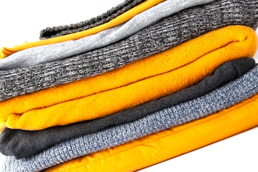 Pile of clothes on a white background. Warm knitted jumpers and sweaters in stack. Home storage. photo