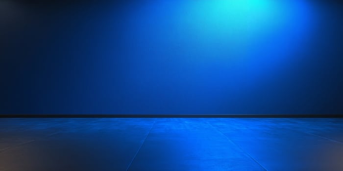 an empty room with blue lights and a black floor photo