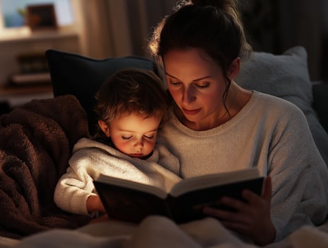 Mother and child reading a book together in cozy evening light. mothers Day photo