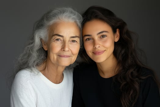 portrait of elderly woman and young woman embracing smiling with gray background. mothers Day photo