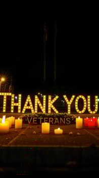 Brightly lit message honoring veterans at a nighttime memorial event with candles photo