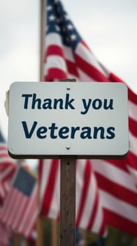 Sign expressing gratitude towards veterans displayed against a backdrop of American flags photo