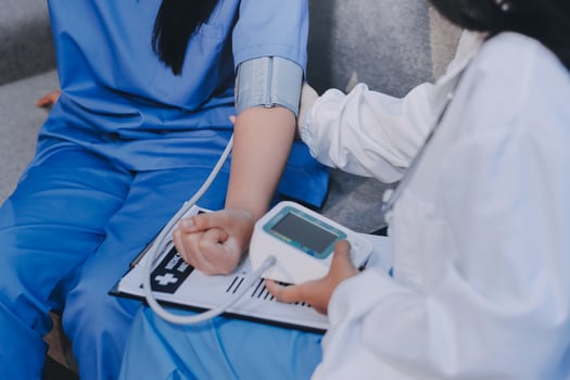 A woman in scrub clothes is holding a blood pressure monitor photo
