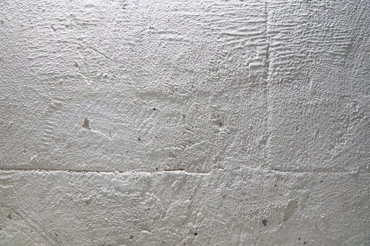 The grainy texture of a stone white wall. Uneven surface with space for copying photo