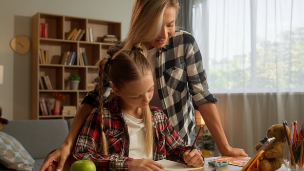 Caucasian little pupil daughter child girl learner writing homework education draw copybook family loving mother female lady mom woman parent touching kid student schoolgirl domestic learning at home photo