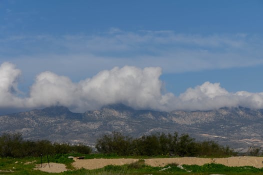 Majestic mountains shrouded in clouds contrast with vibrant greenery under a clear blue sky photo
