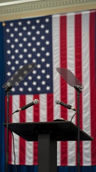 Podium with two microphones, American flag backdrop, suggesting a political event. Vertical Mobile Wallpaper photo