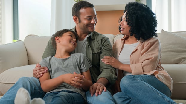 Happy multiracial family parents and joyful little boy kid son on floor laughing having fun African American mom dad talking with child celebrate relocation day weekend at home upbringing parenthood photo
