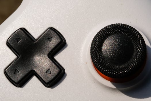 Black Directional Pad on a white Game controller. Directional pad is used to move focus up, down, right, and left in the user interface. Hobbies and leisures. Negative Space photo