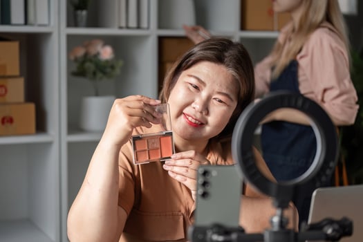 Makeup guru presenting a cosmetic palette during a live demonstration from her contemporary home studio photo
