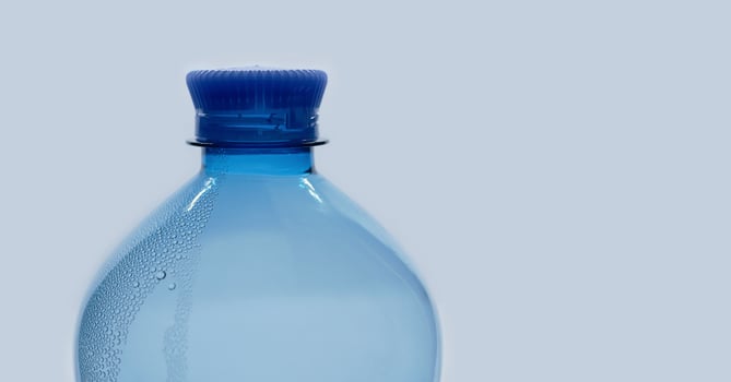 A blue plastic PET water bottle close up isolated on white background with bubble condensation on the surface. Recycling, environment friendly and ecology concept photo