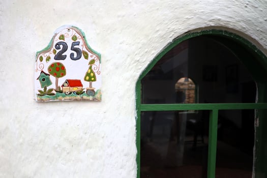The charming and inviting House Number 25 is beautifully displayed on a white wall photo