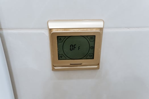 A sleek and modern digital thermostat is noticeably mounted on a pristine, white wall, effectively highlighting its advanced design and multifunctionality within this contemporary space photo