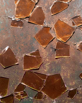Broken amber glass pieces on a rusty surface photo