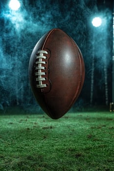 American football levitating over a smoky field at night photo