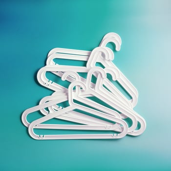 Group of White Plastic hangers as minimal layout on soft gradient background of teal tones, Clothes rack for organizing clothes in closets or retail stores for hanging of garments, top view photo