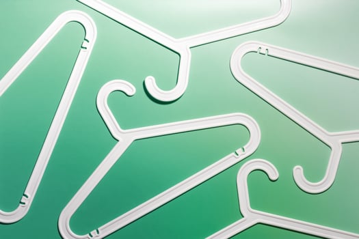 Top view minimal style pattern of white plastic hangers with hooks on white green background. Flat lay with Clothes rack for hanging garments. Minimal trend photo, lifestyle or interior design concept photo