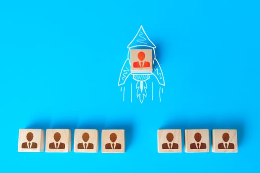 A human figurine flies out of a row of colleagues on a drawn doodle rocket. Promotion at work, appointment to team leader. Initiative and aspiration. Impressive success, a business career accelerator. photo
