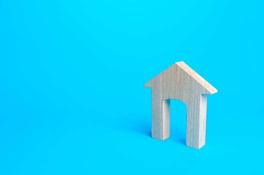 Wooden house figure on a blue background. Affordable comfortable housing concept, new home. Mortgage. Real estate, rent and sale. Realtor services. Copy Space photo