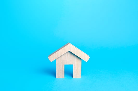 Small house figurine on a blue background. Minimalism. Affordable housing. Rent of real estate. Construction industry. Utility services. Realtor services. Repair and renovation, modernization. photo