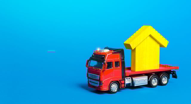 Red freight truck carrier with a yellow house figure. Home moving company. Transportation service and delivery of complex and oversized cargo. Cargo insurance photo