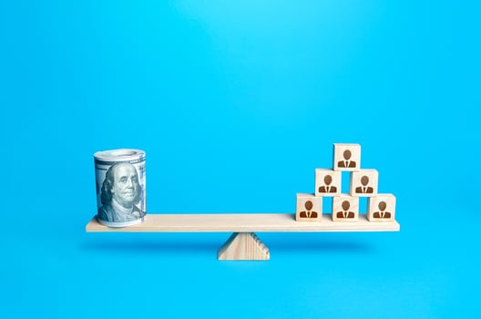 People blocks pyramid and rolled up bundle of dollars on scales. Financing the company and remuneration of staff. Organization accounting. Investments in human capital. Tax collection. Salary fund. photo
