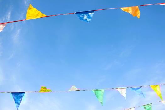 Vibrant and Colorful Festival Bunting Hanging Beautifully Against a Bright Blue Sky Above photo